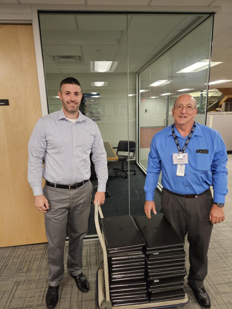 Pictured is Tighe & Bond Business Technology Manager, Daniel Carney with Helix Human Services Information Technology Manager, Daniel Beaudoin and a stack of laptops part of the IT donation.
