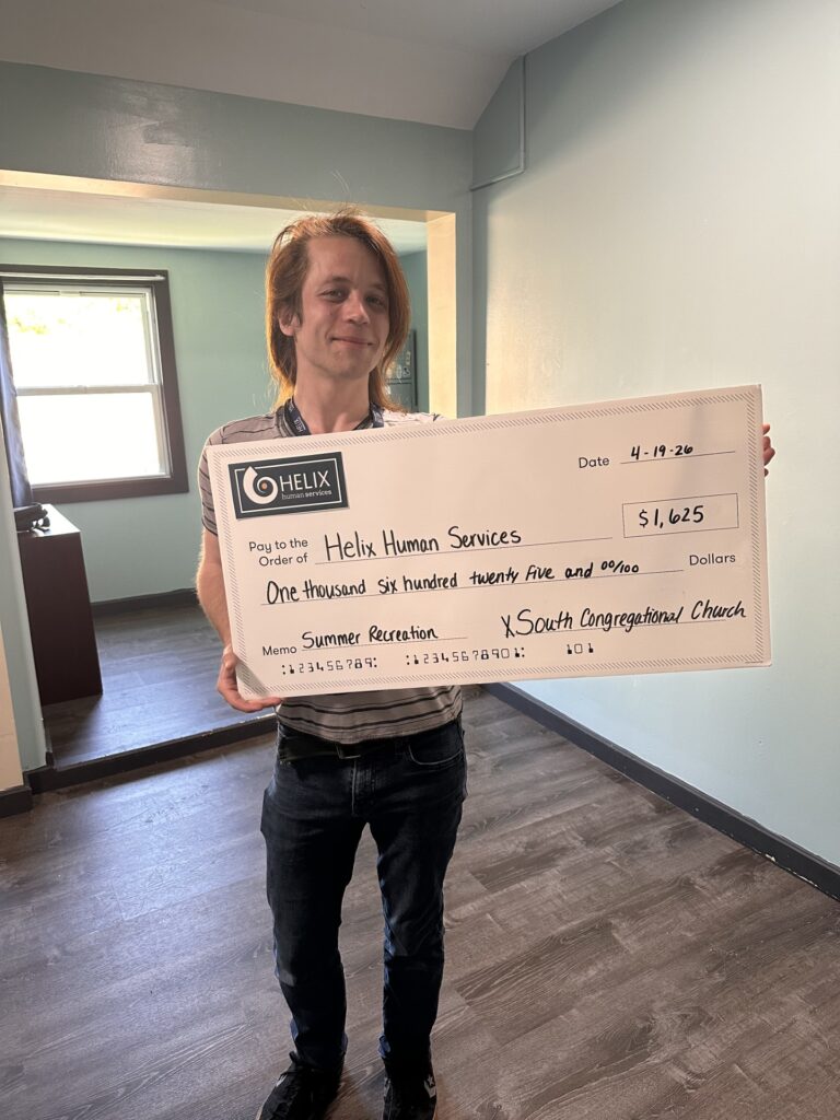 Residential staff Ben McLaughlin holding a grant check.